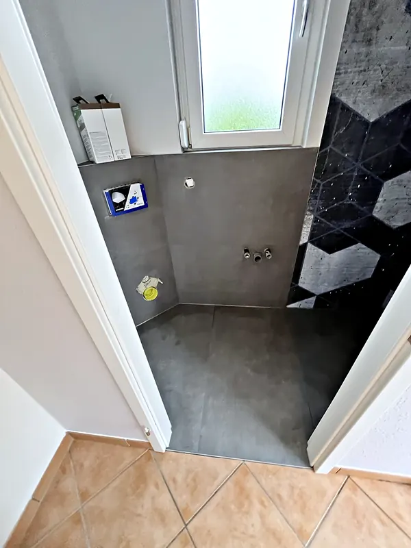 Bad mit dunklen Großformatfliesen und Vorwand